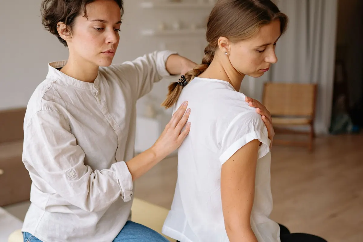 Therapist working on a seated client's shoulder during a sports massage